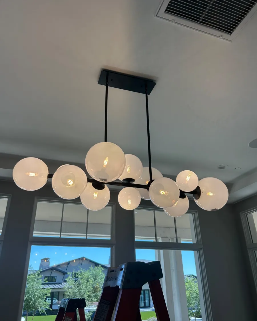 Linear globe chandelier being installed over a dining area